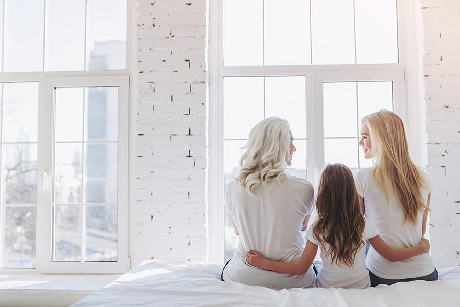 Tři generace žen sedí spolu na posteli